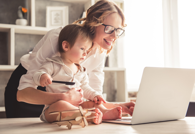 Mum holding daughter while working from home on a laptop